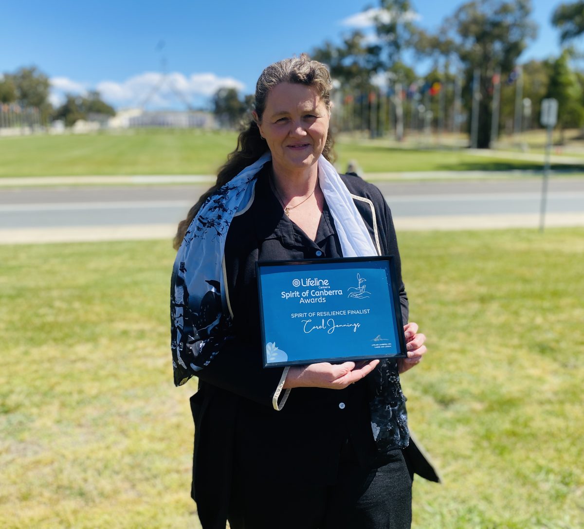 Carol Jennings with award in front of parliament house 