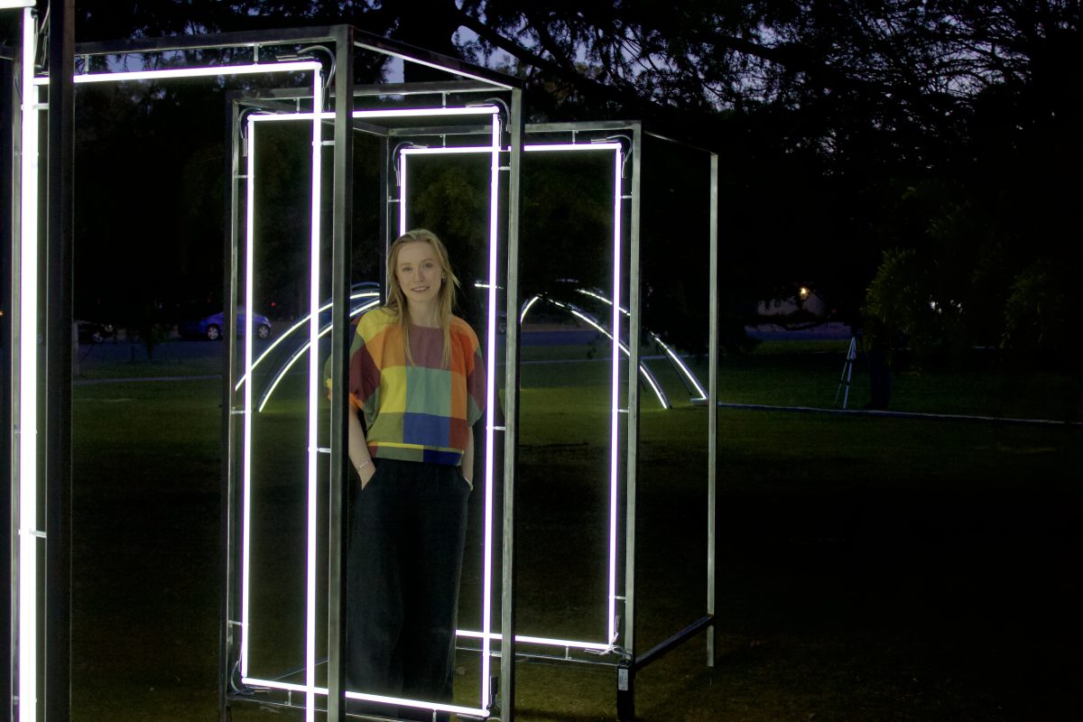 Sculptor Bronte Cormican-Jones standing in a light installation