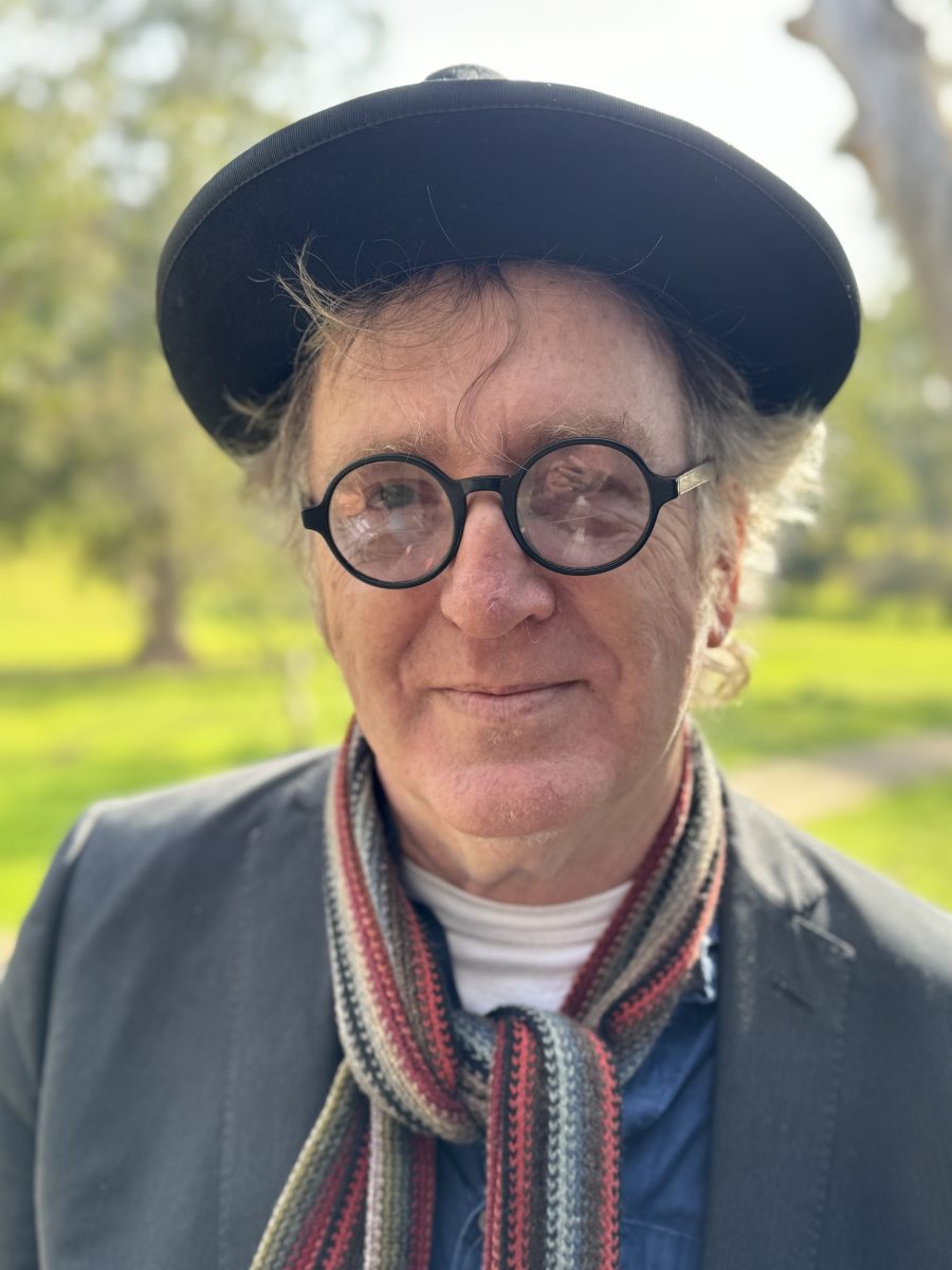 Head and shoulders of man in hat, scarf and cool sunnies.