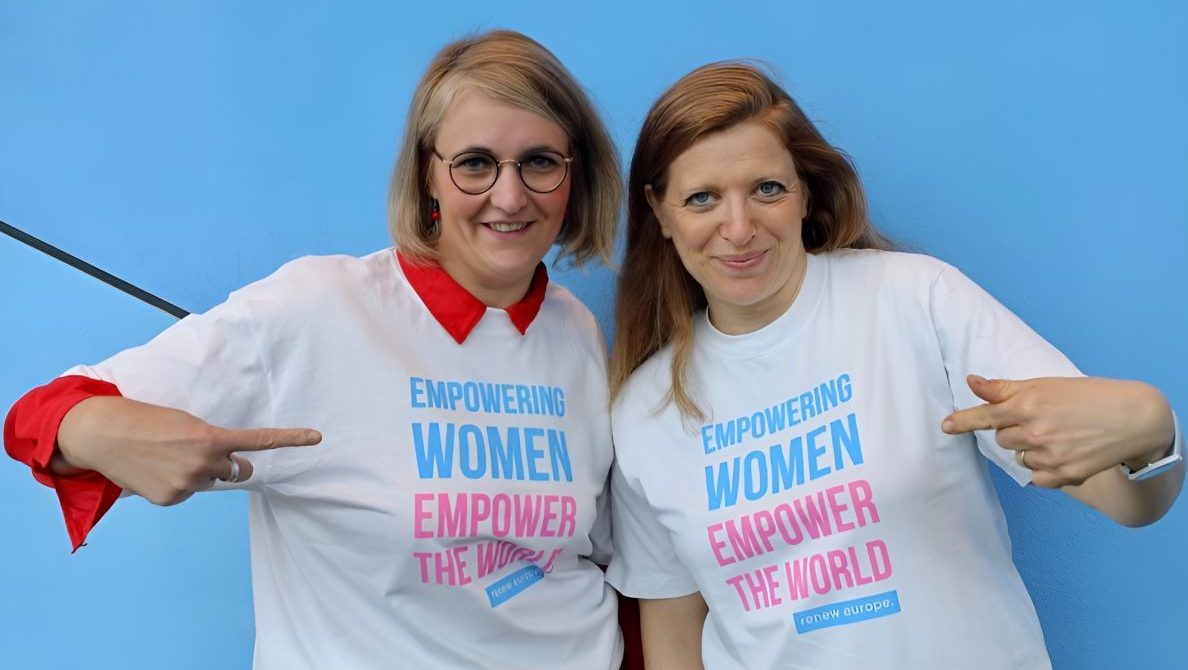 two women point to their shirts