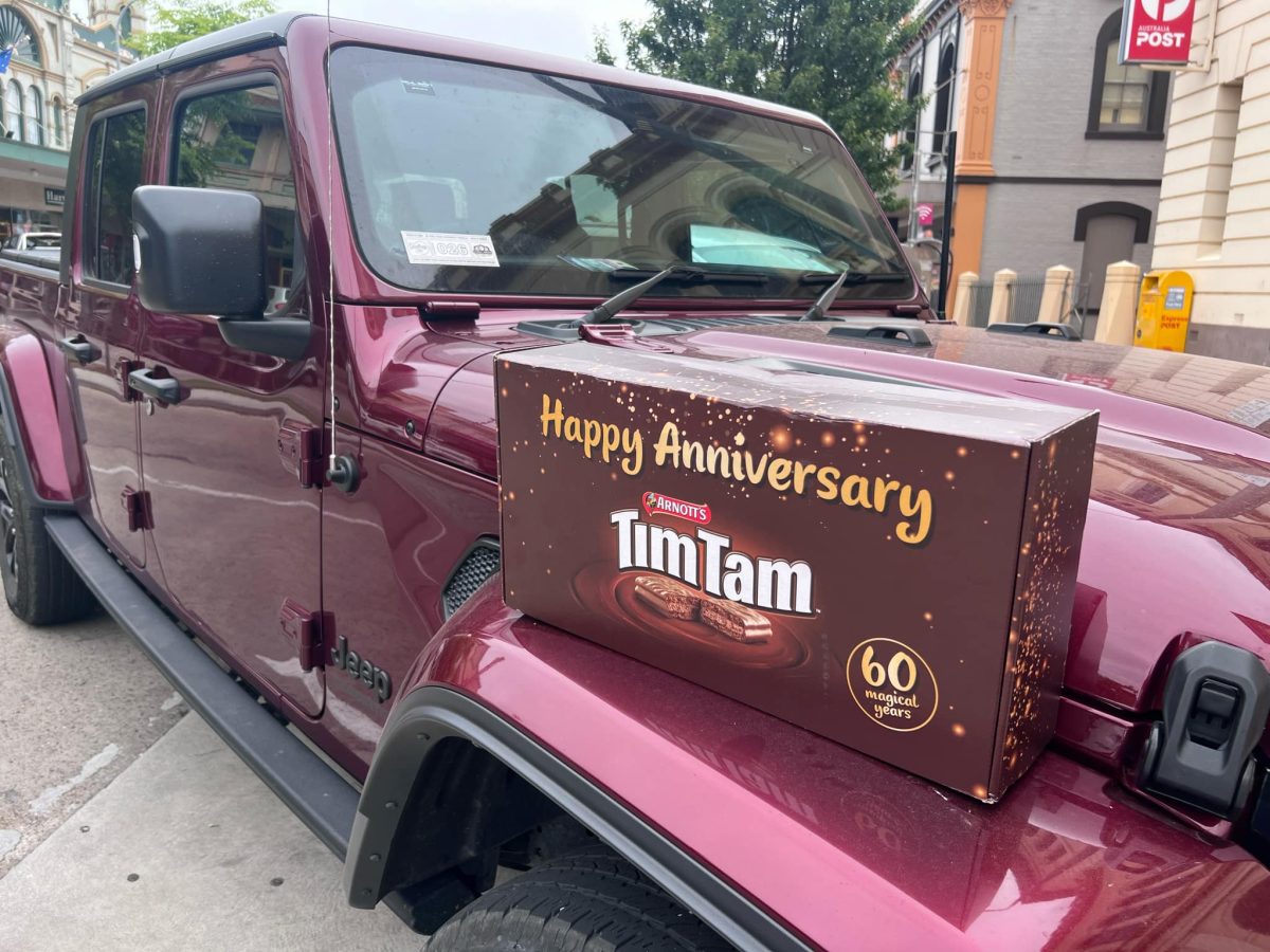 A box of Tim Tams sits on a Jeep.