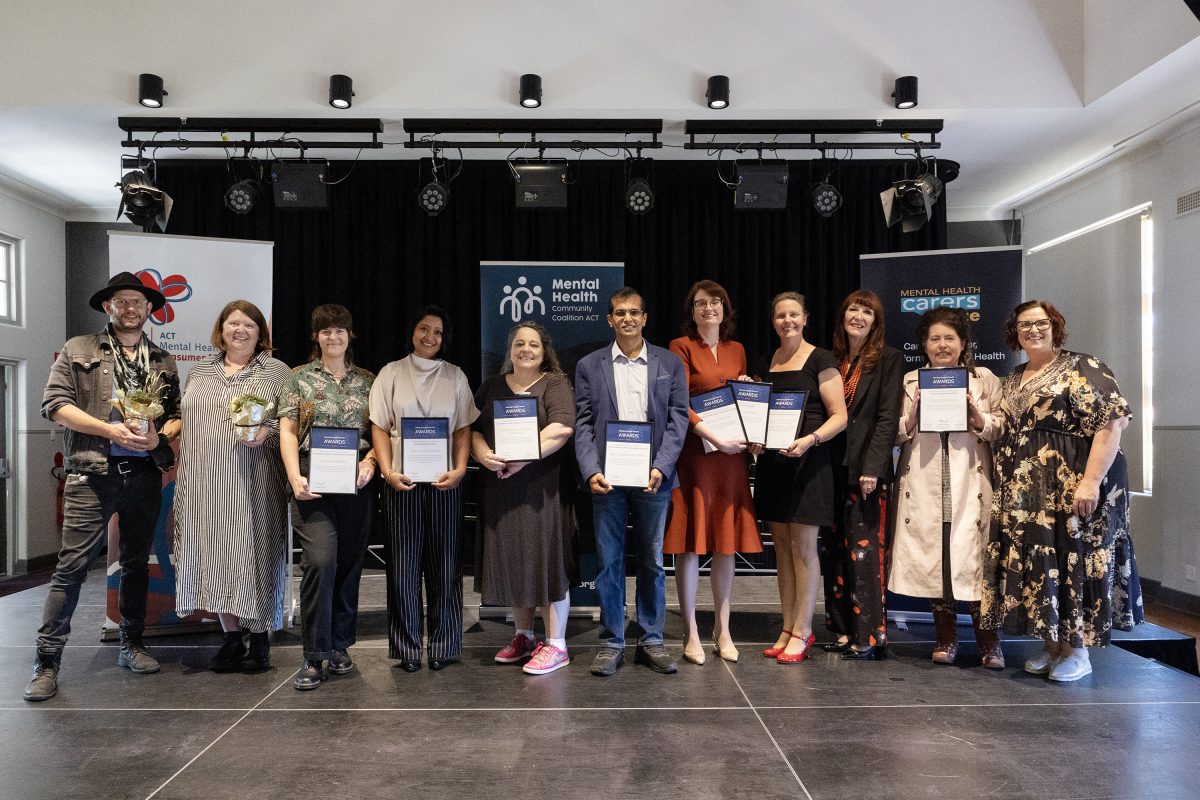 eleven people holding awards in a hall