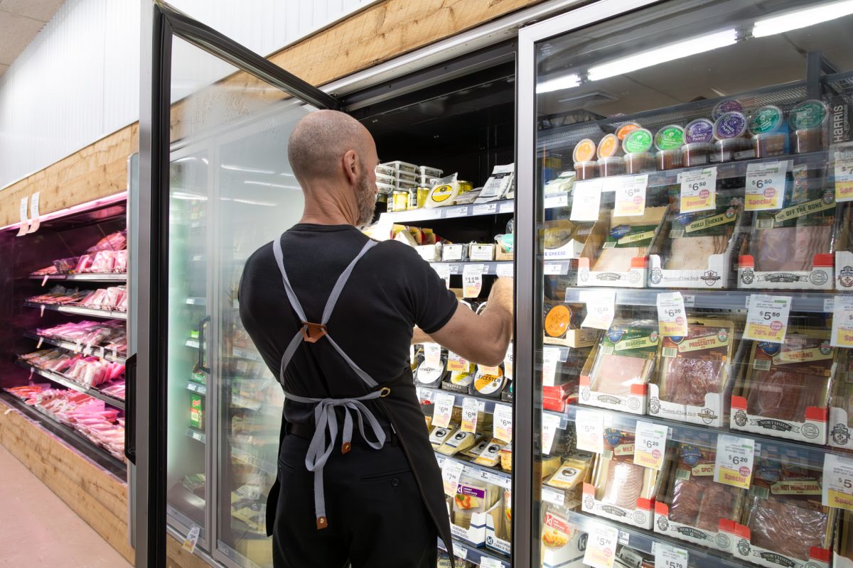 man stocking cheese products in fridge