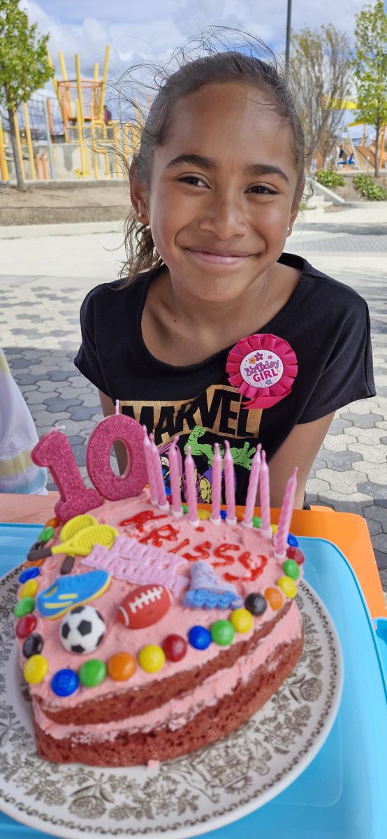 young girl with birthday ribbon and cake