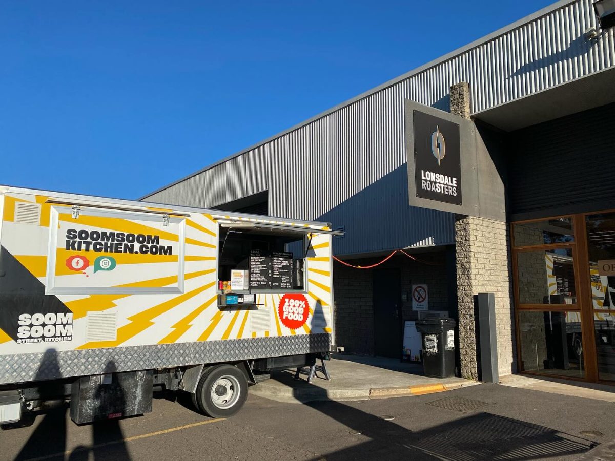 A yellow striped food truck parked outside a warehouse