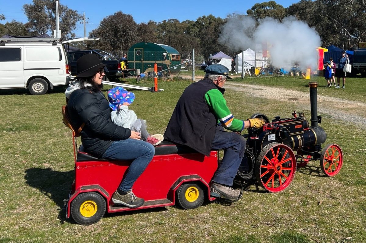 man driving woman and child on mini steam train