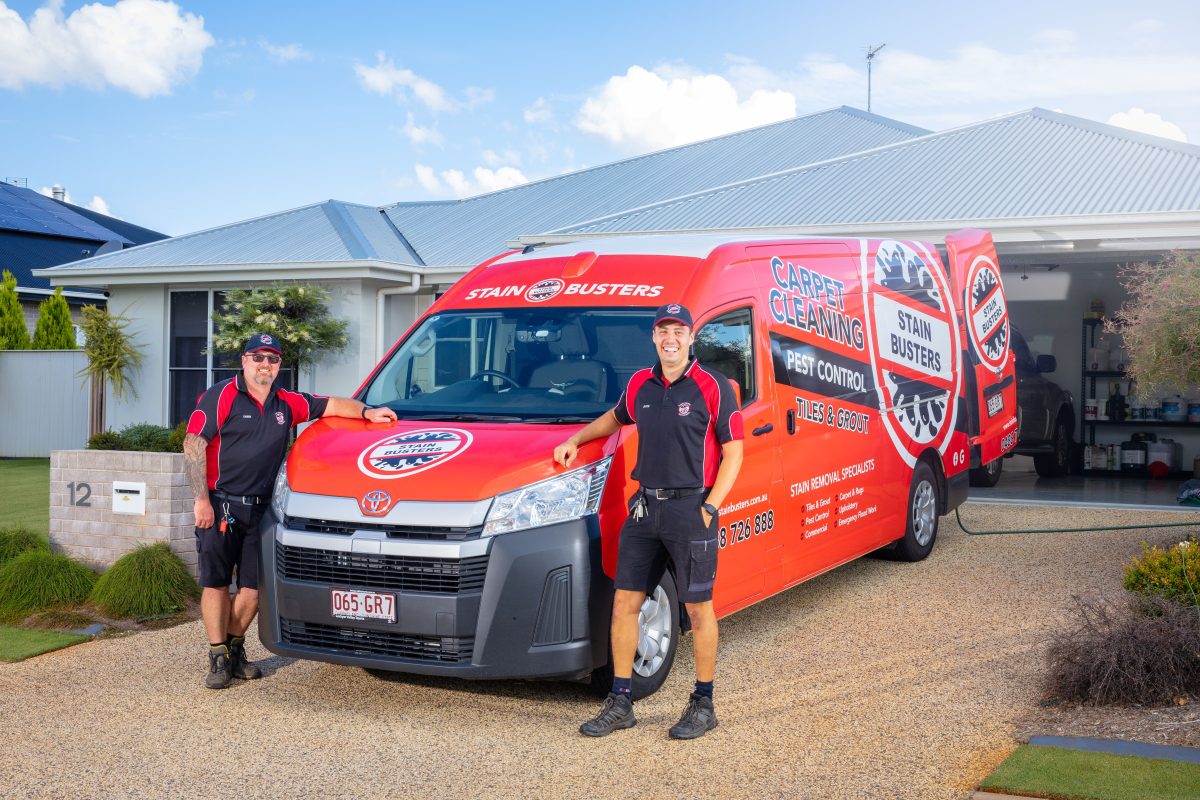 Two men standing next to a company van