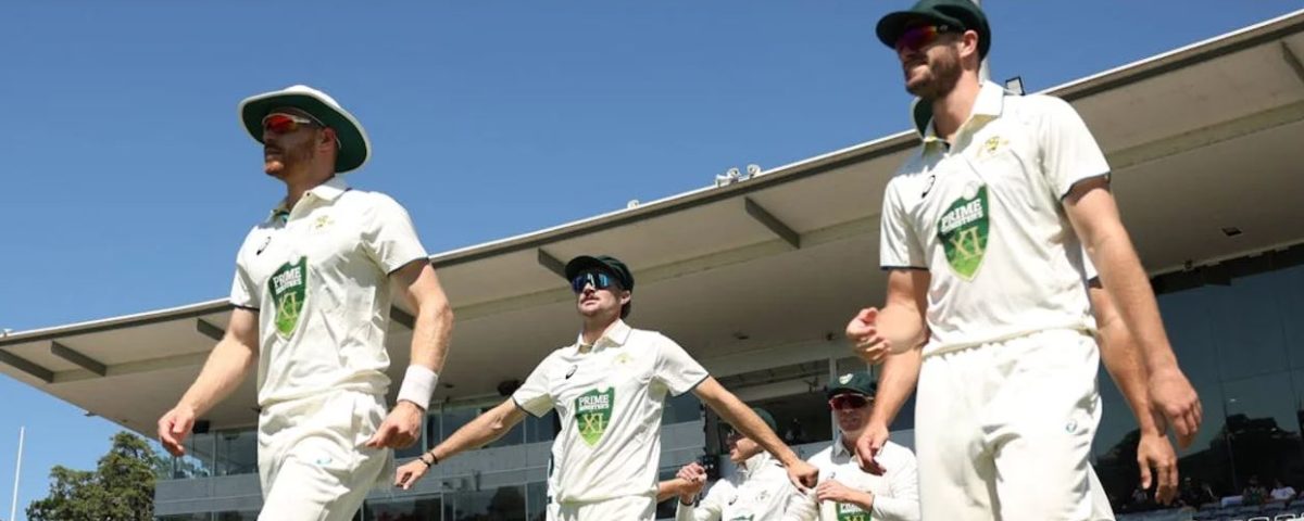 Three cricket players walking onto the pitch