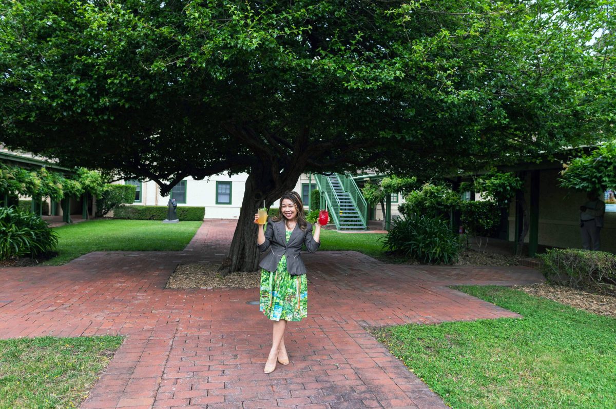 woman holding gin in front a large tree