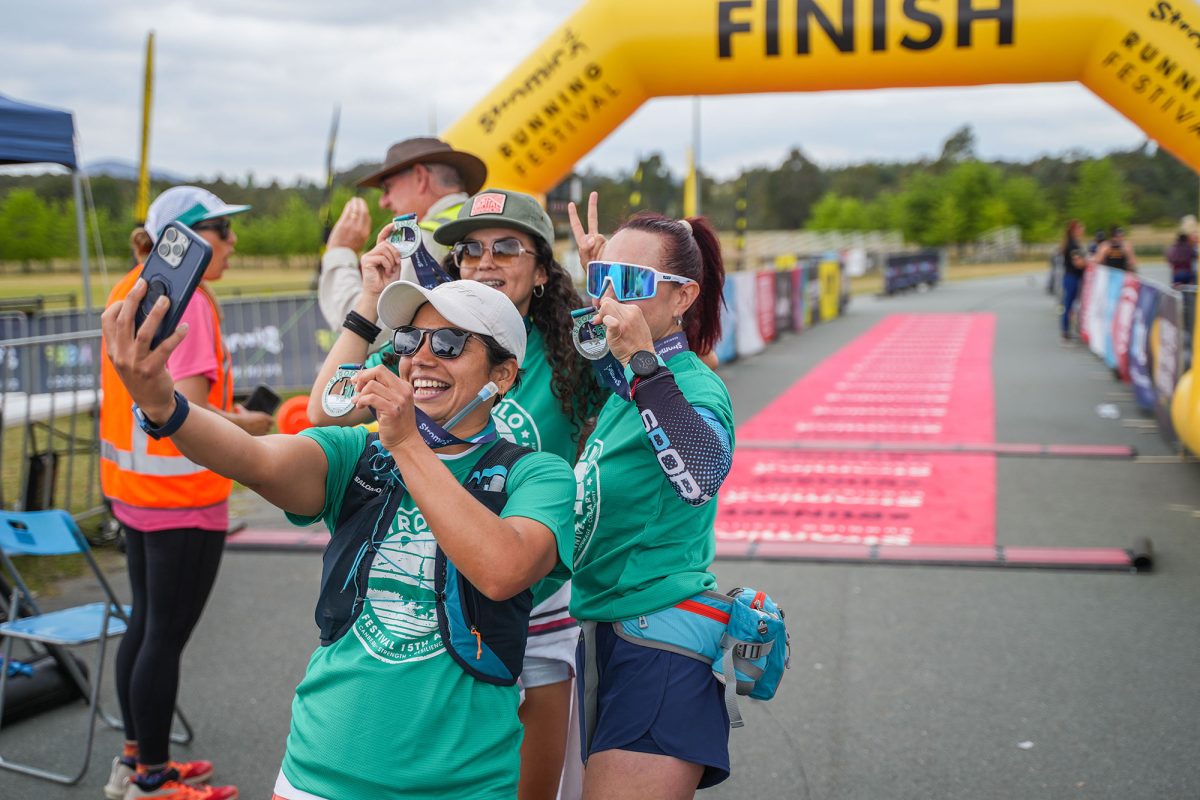 three people holding medals at the finish line