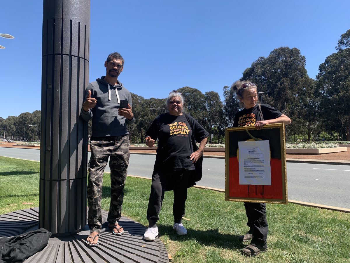 Three Indigenous people standing beside Anzac parade.