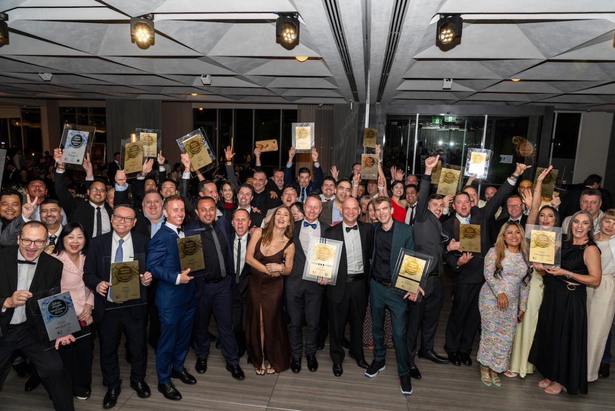 A group photo of many people holding awards.