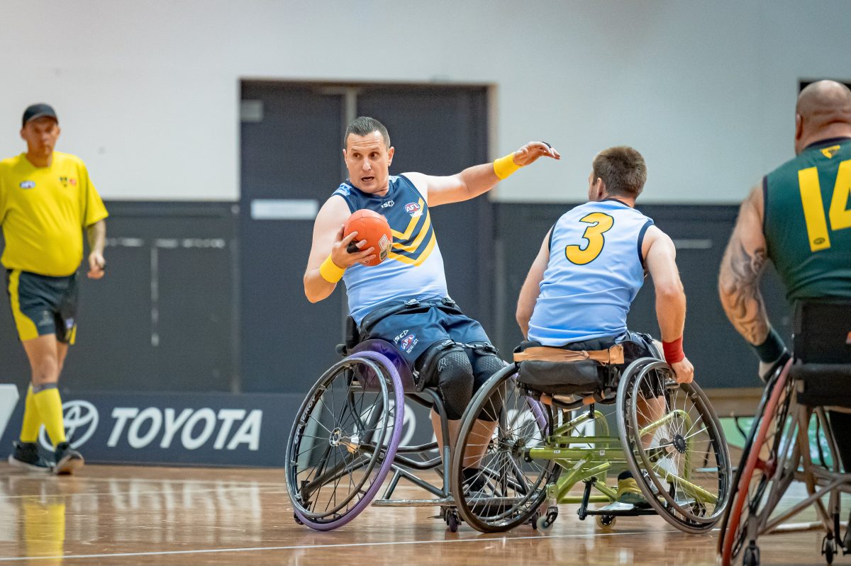 wheelchair AFL player with ball in hand 