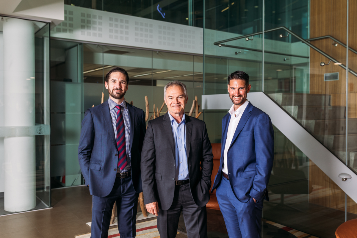 three men in suits standing in the foyer of an office building