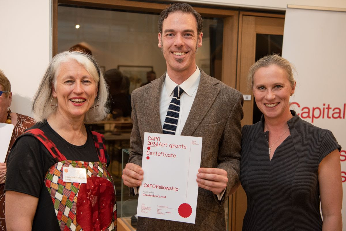 Two women and a man holding a certificate