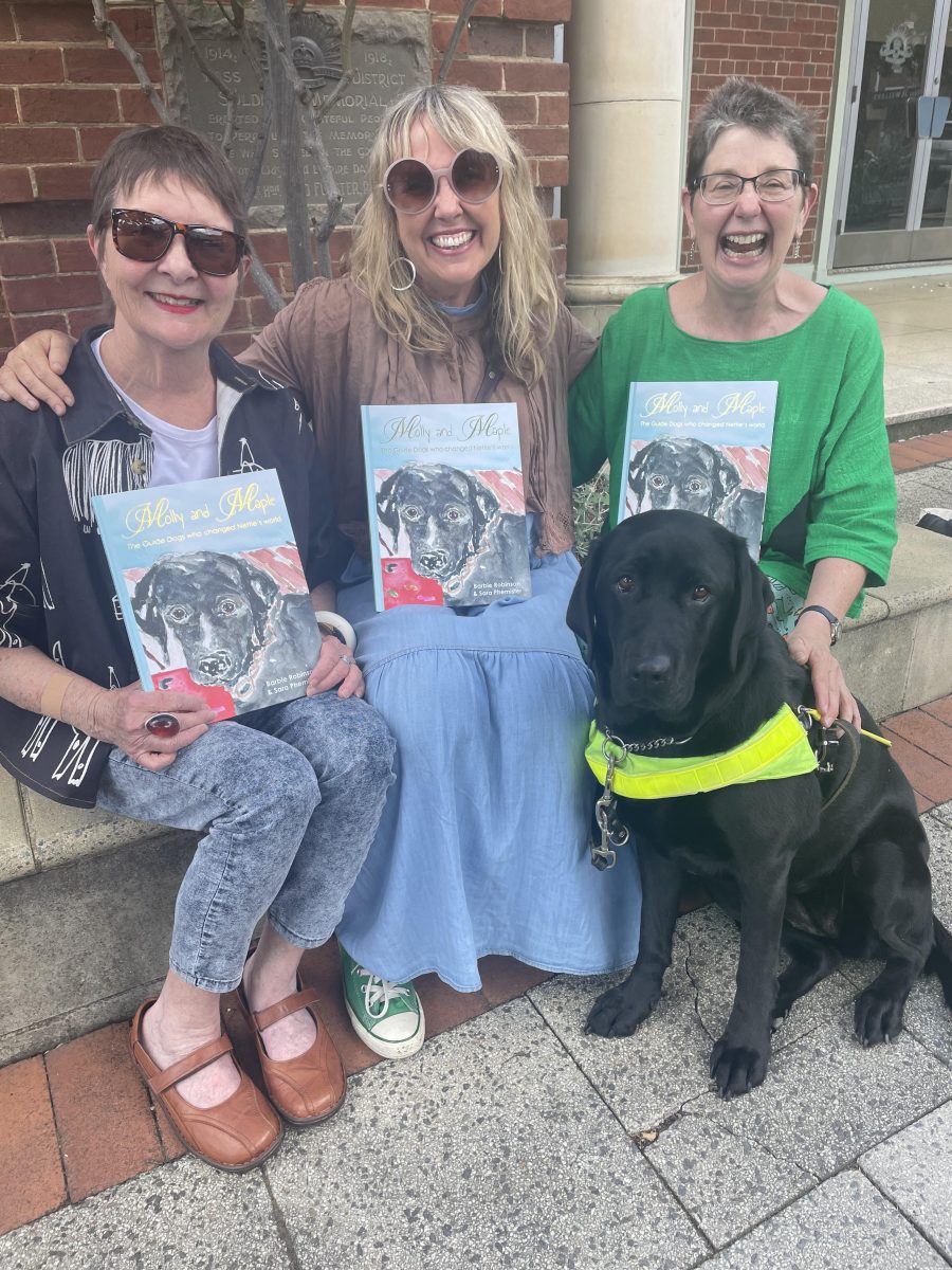 Barbie Robinson, Sara Phemister and Annette Holden, all holding the book Molly and Maple, with Annette's dog Maple.