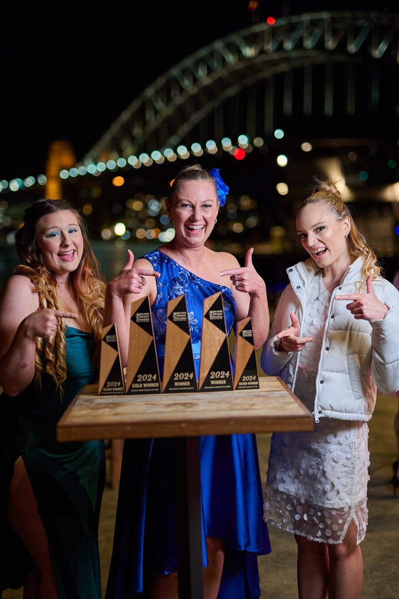 Bom Funk's Zoe Tuckfield, Kym Degenhart and Shekiralea Healy celebrate with trophies near the Sydney Harbour Bridge