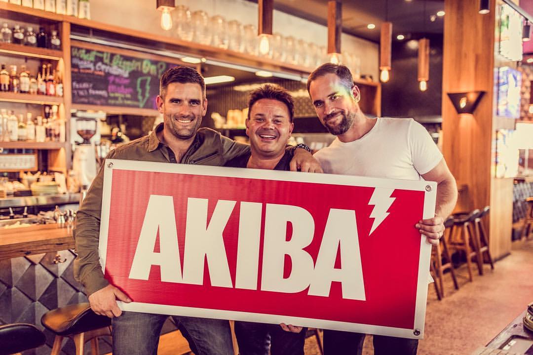 Three men hold the Akiba sign.