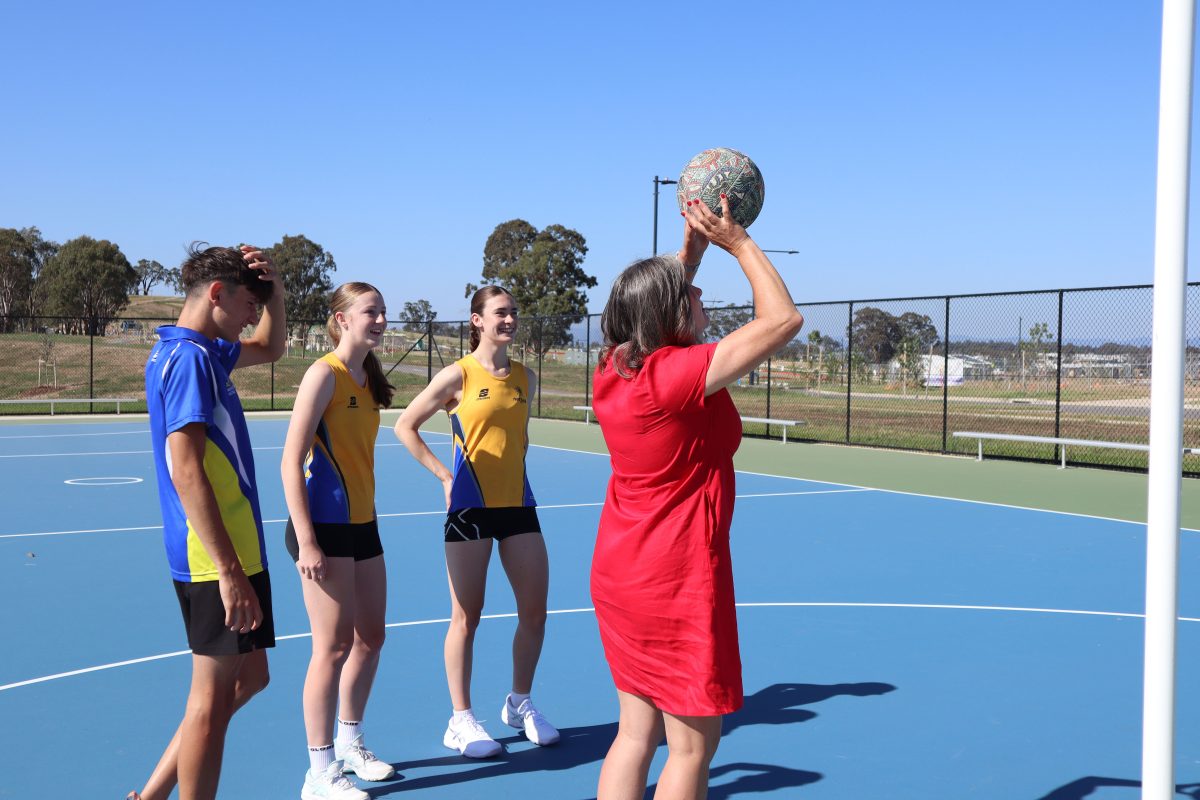 Yvette Berry tries her hand at netball at the new courts in Jacka watched by three players.