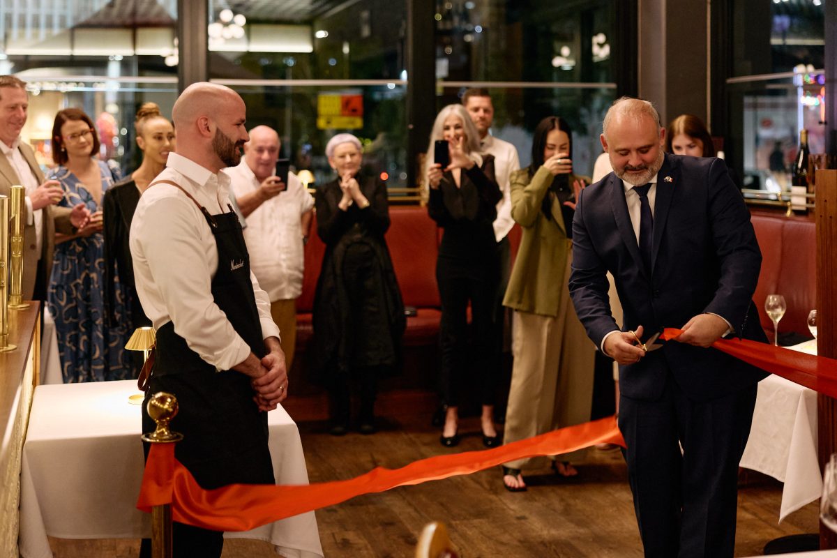 A crowd applauds as French Ambassador Pierre-André Imbert cuts the ribbon at Montrachet.