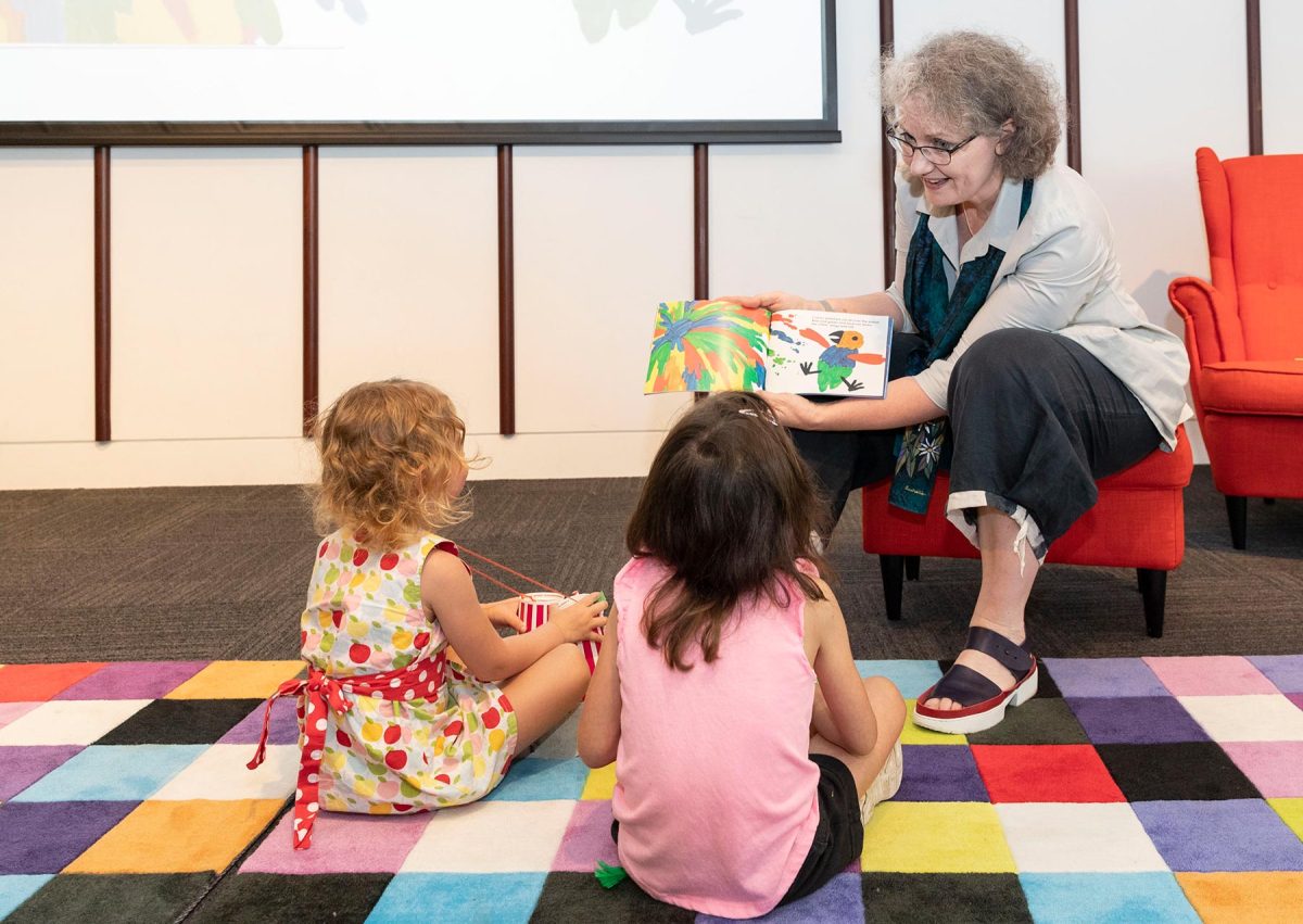 Woman reading two children a book 