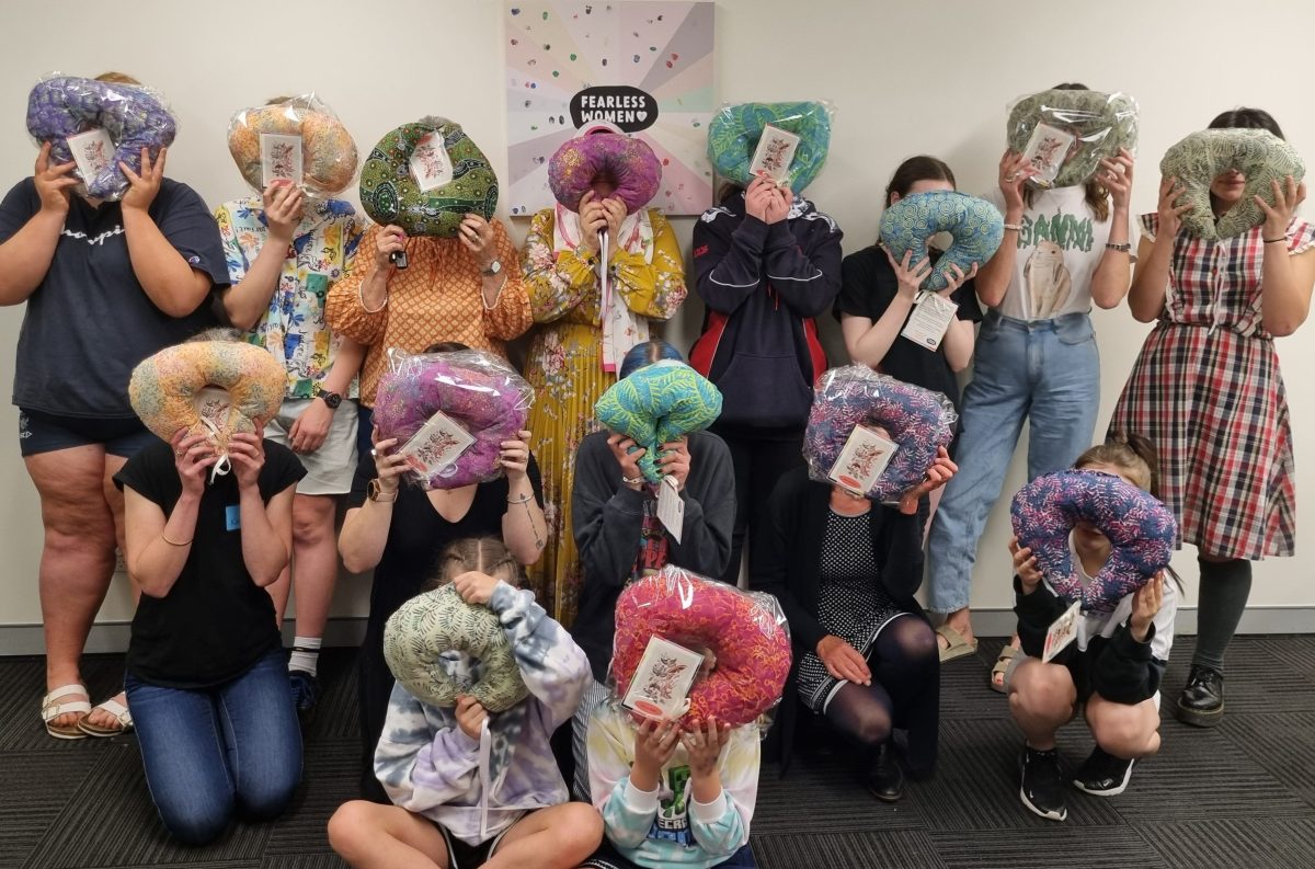 Women hold hand-made neck pillows over their faces