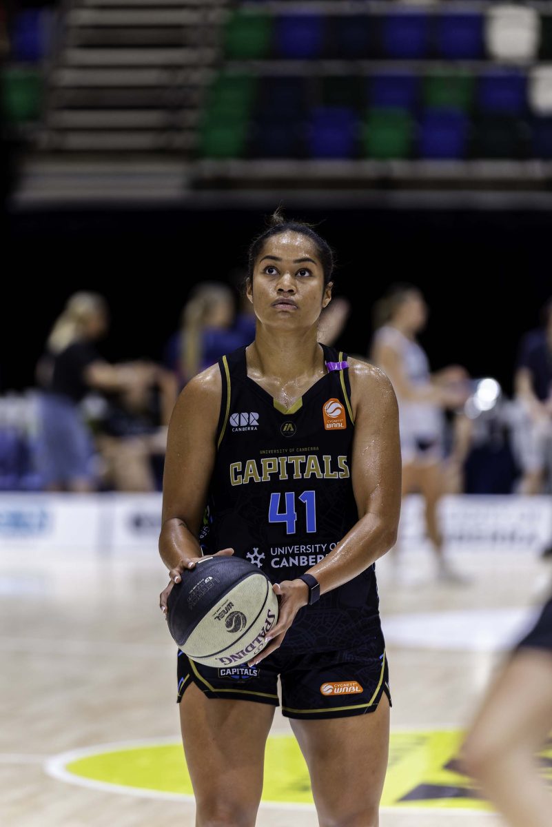 a UC Capitals basketball player holding a basketball looking in the distance