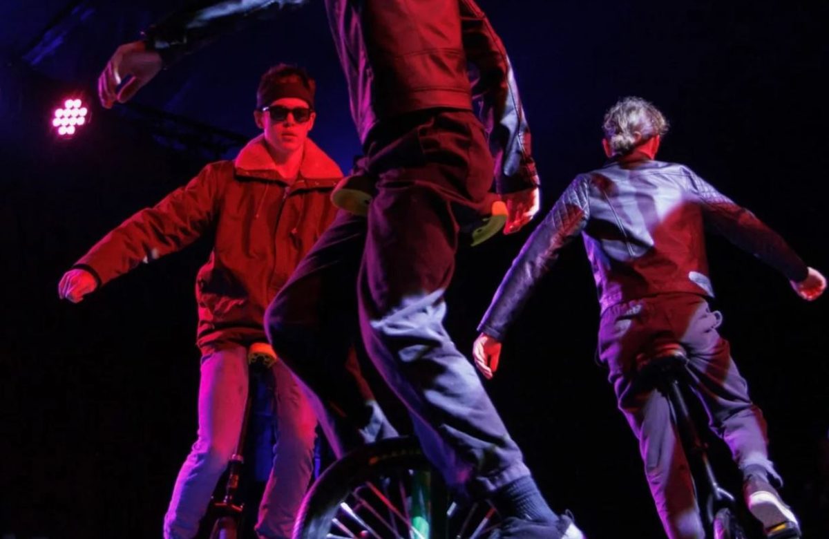 Three people on stage in red lighting during the warehouse circus school holiday program