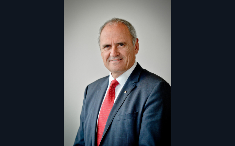 A headshot of Dr Ken Henry AC in a suit and red tie.