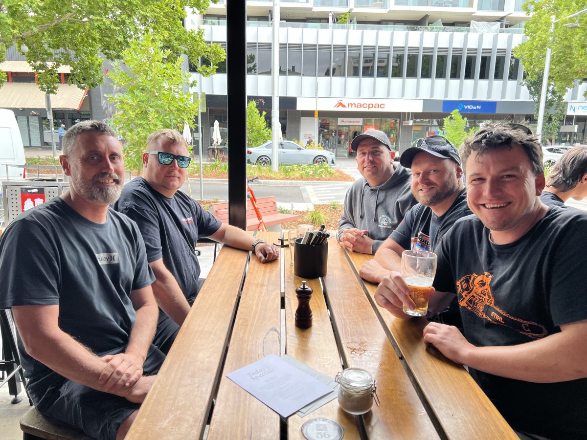 A group of men sitting around a table drinking beer.