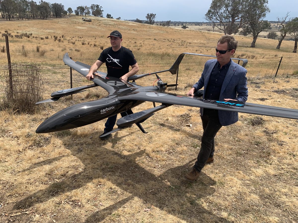 Two people walking while holding a drone.