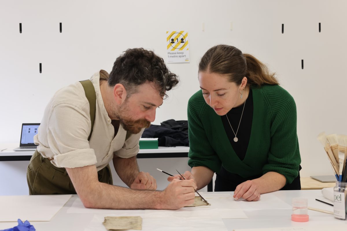 two people working on an old book