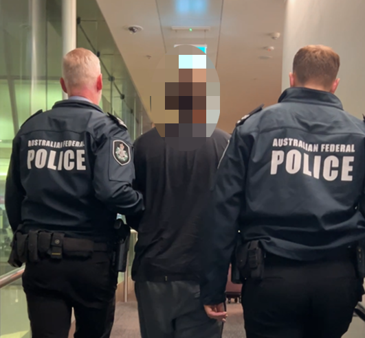 two police officers escort a man in custody