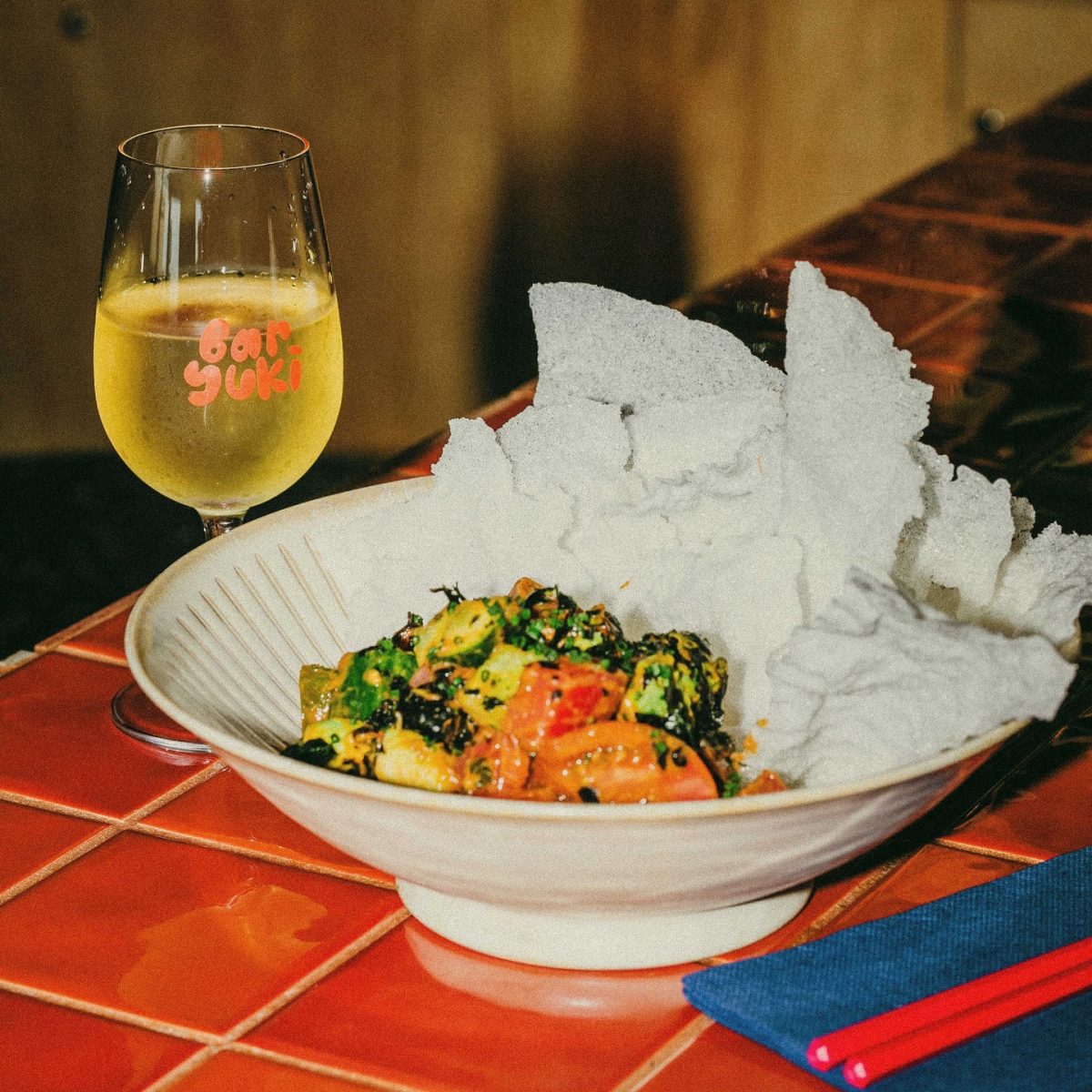 A wine glass reading 'Bar Yuki' in bubble writing and a bowl of food.