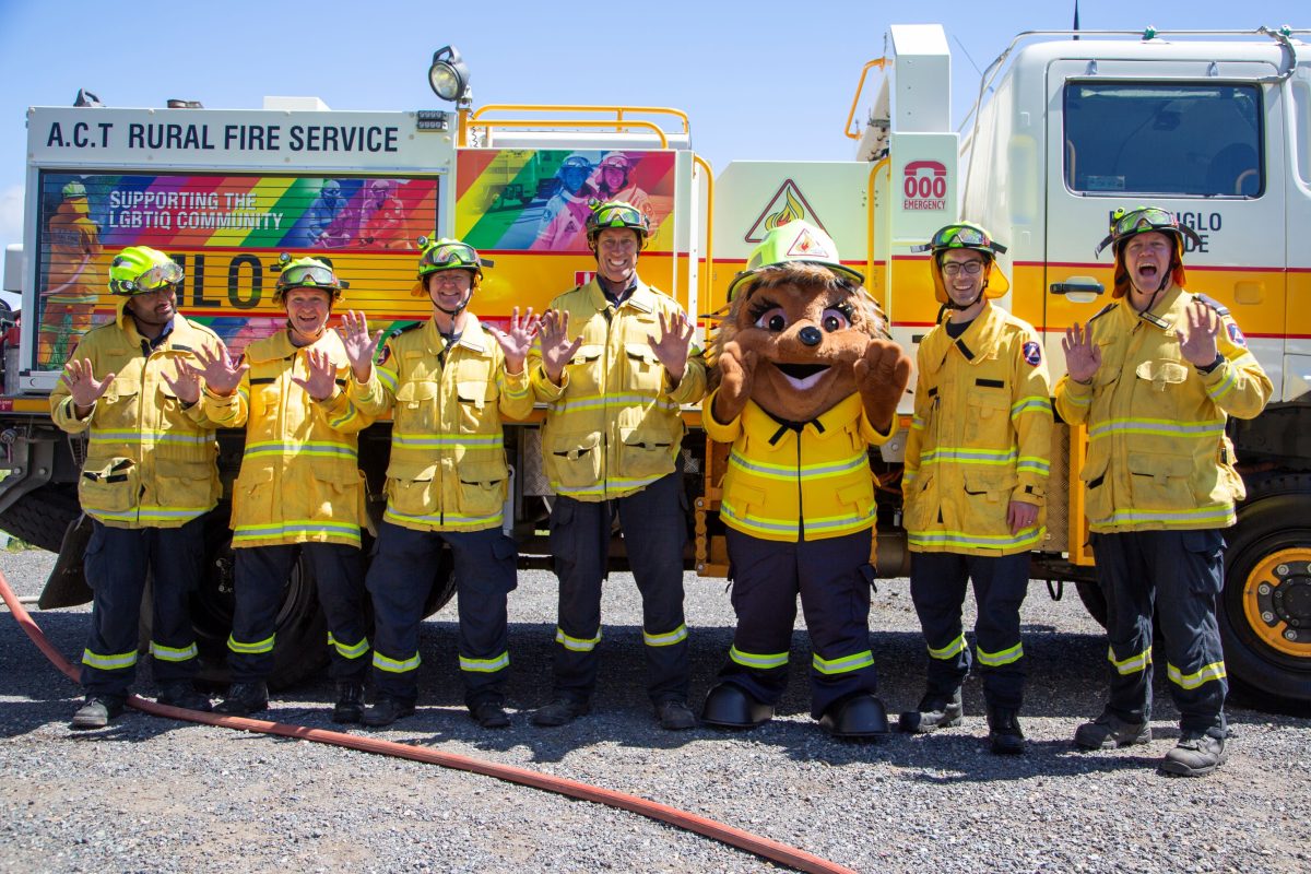 Six firefighters in front of truck with Ember the echidna mascot