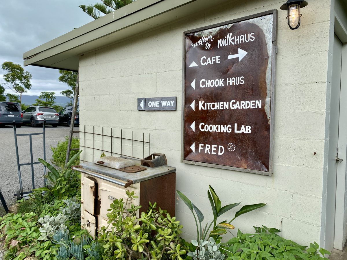 A retro sign pointing towards the cafe, kitchen garden etc. with a garden bed below.