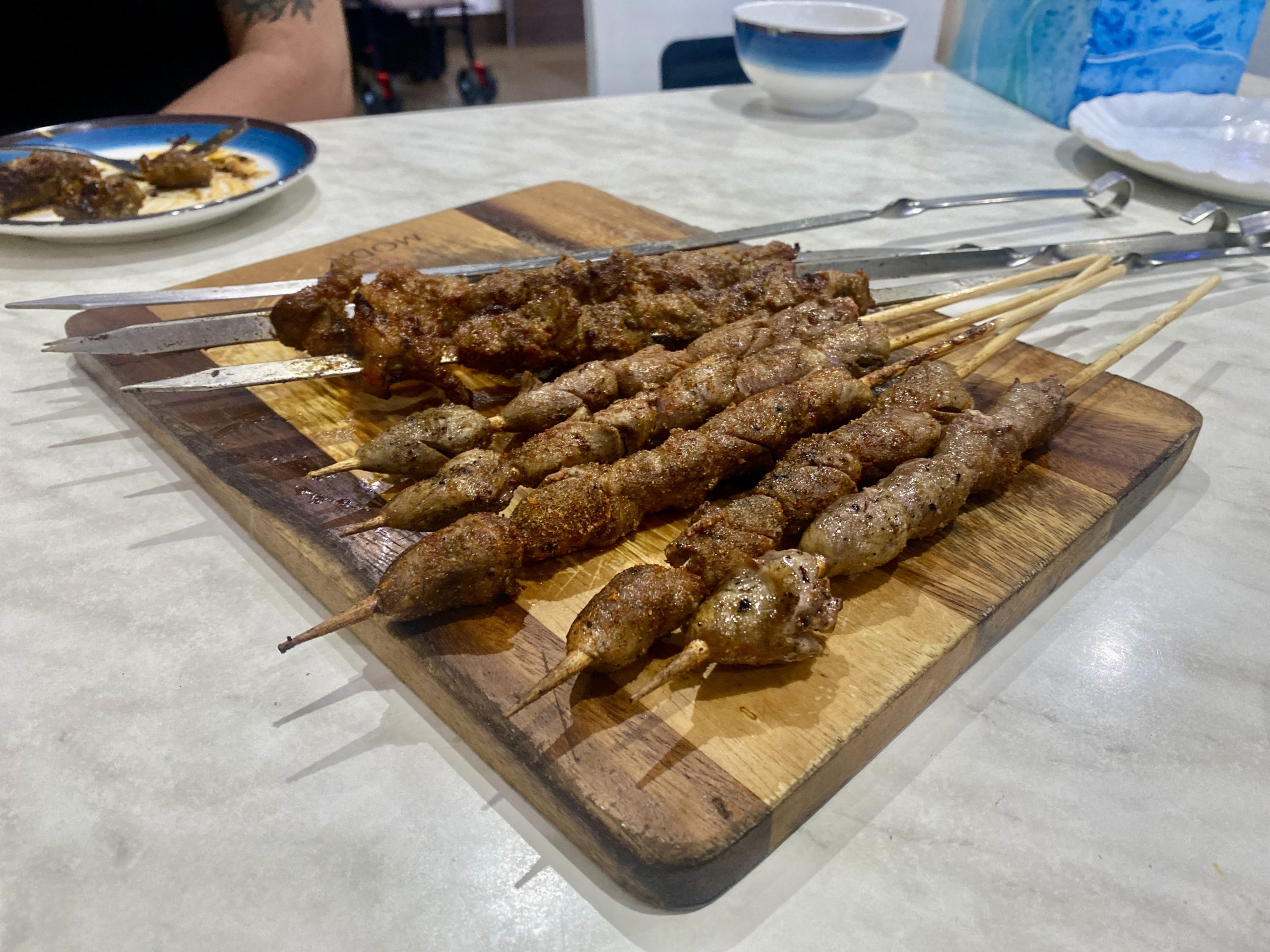 A wooden platter with chargrilled skewers.