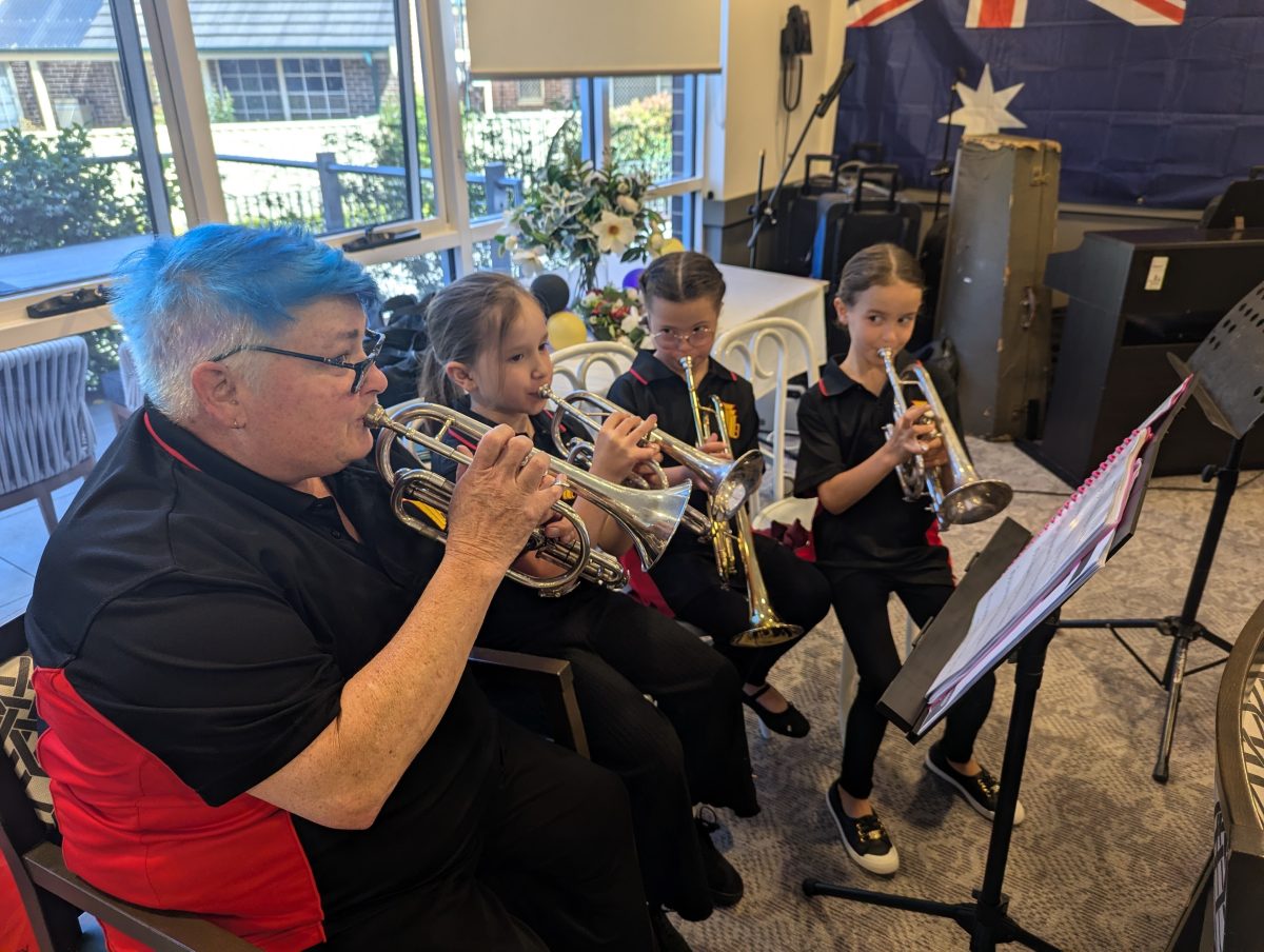 A woman with blue hair playing brass instruments with three children