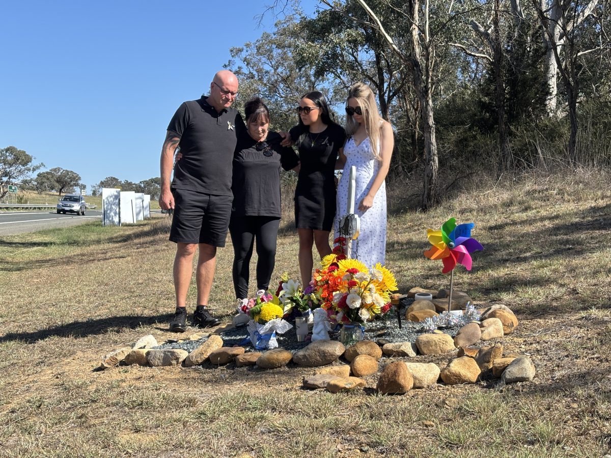 Four people (Jyle Molloy Murphy's family) standing in front of a memorial 