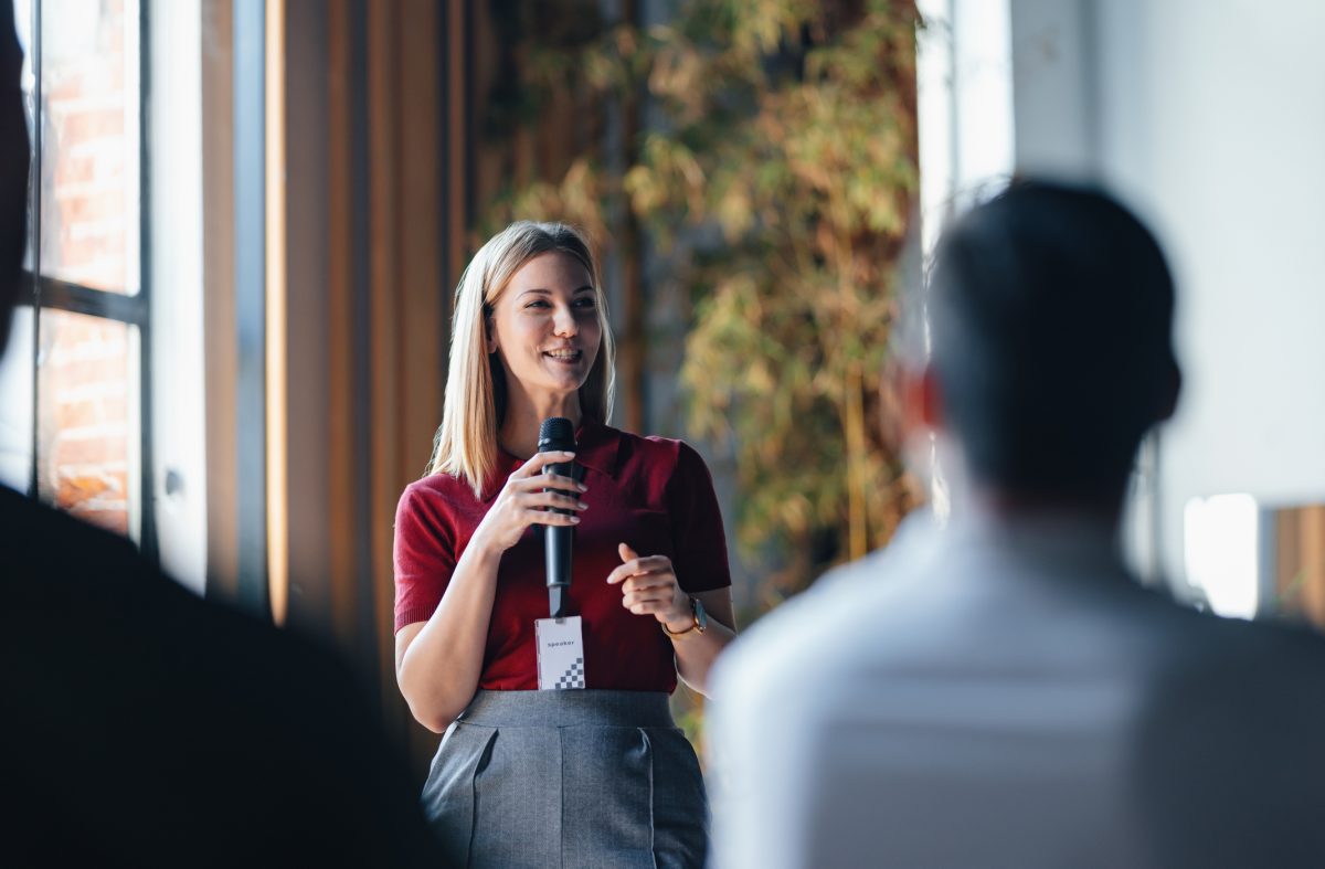 Woman holds microphone and speaks to audience