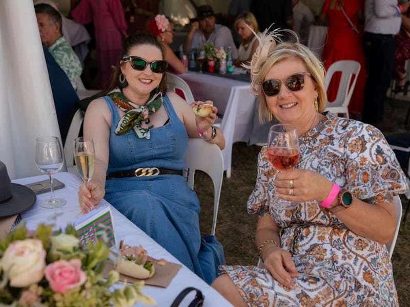 two people dressed up and holding glasses of wine for the Yass Picnic Races