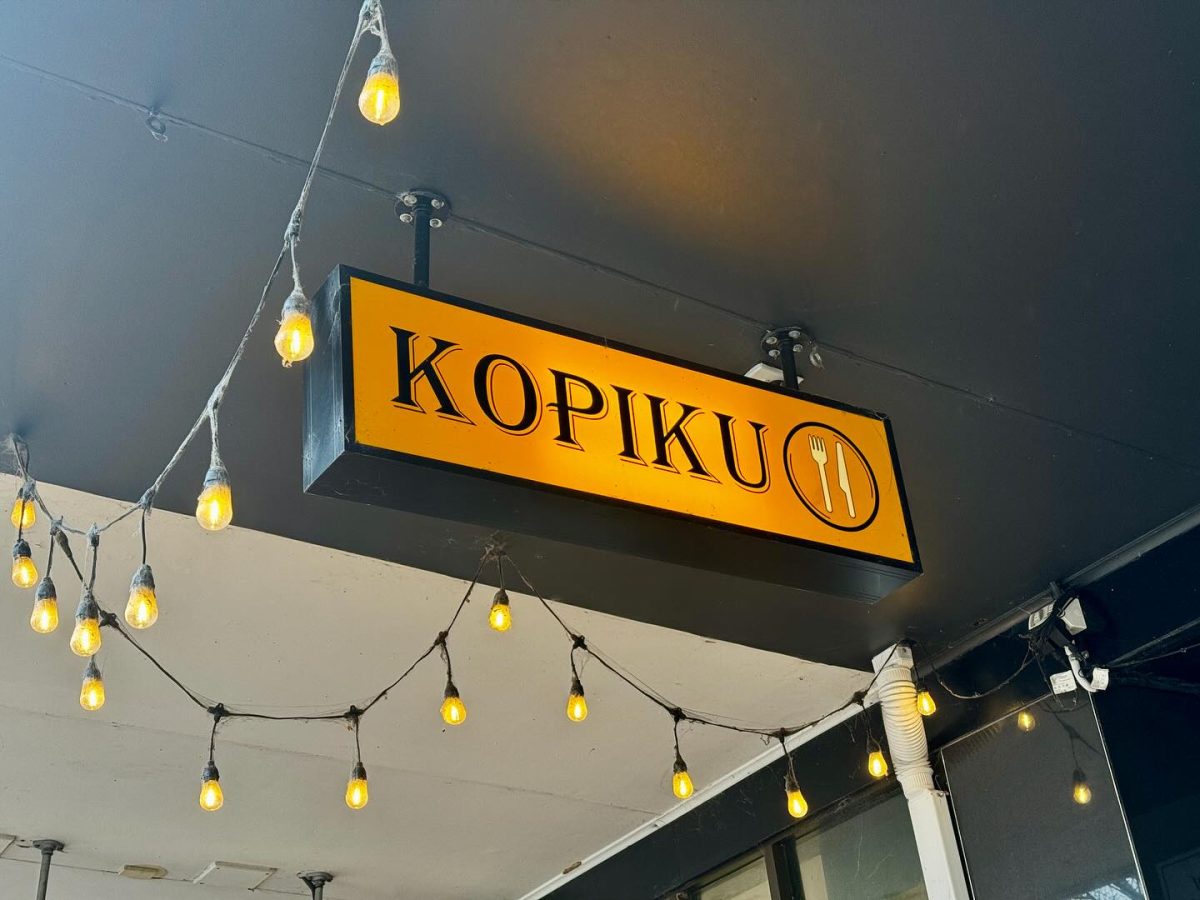 Yellow sign reading KOPIKU, with fairy lights around it.