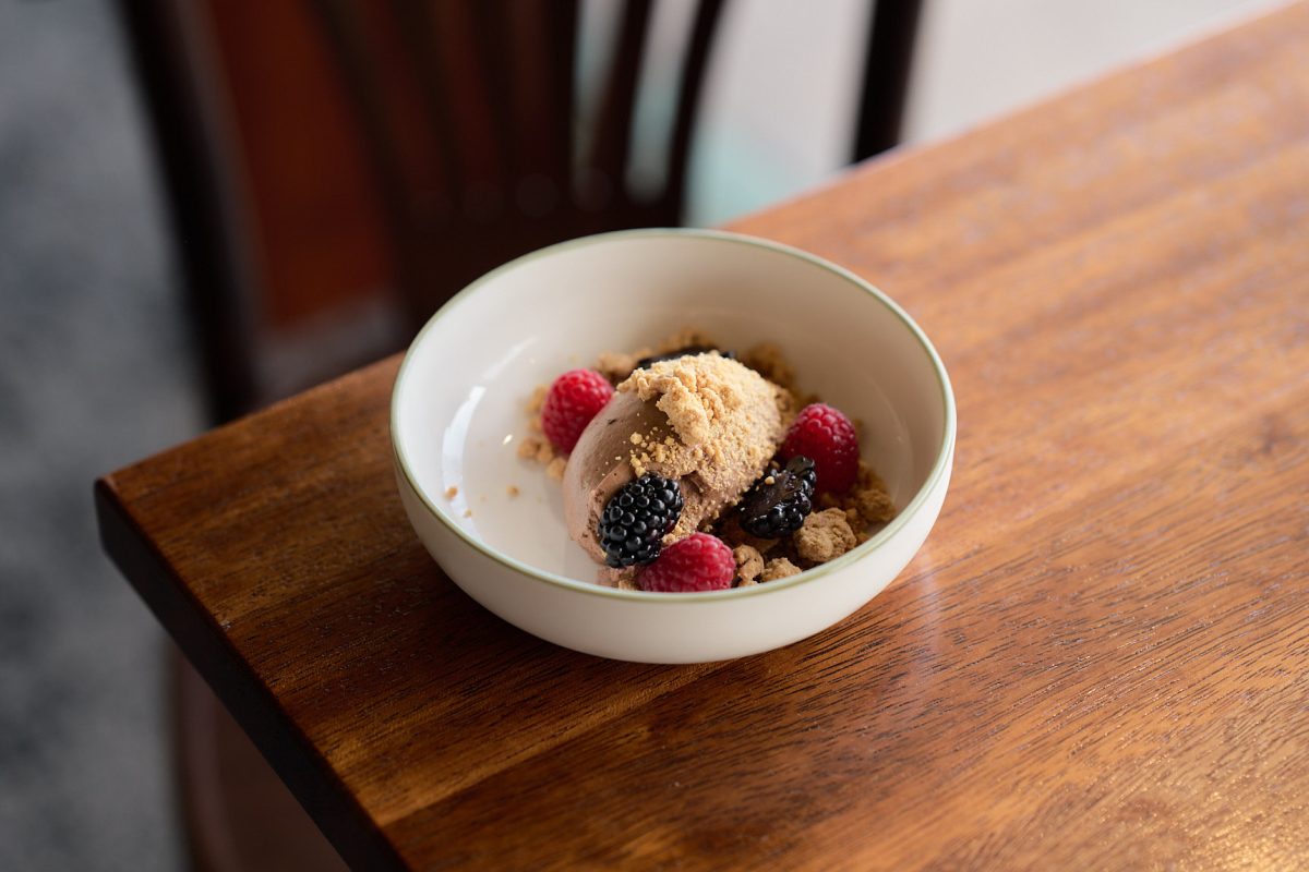 A bowl of chocolate mousse and berries on a table.