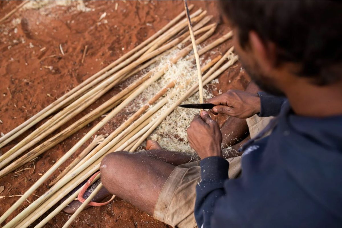 a photo of a man whittling a stick into a spear