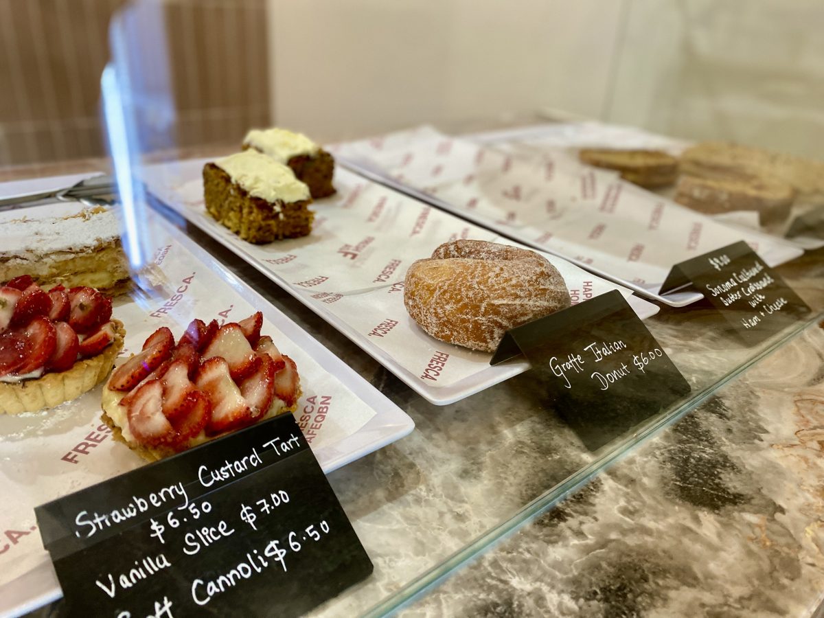 Cakes cabinet with a strawberry tart and sugar coated donut.