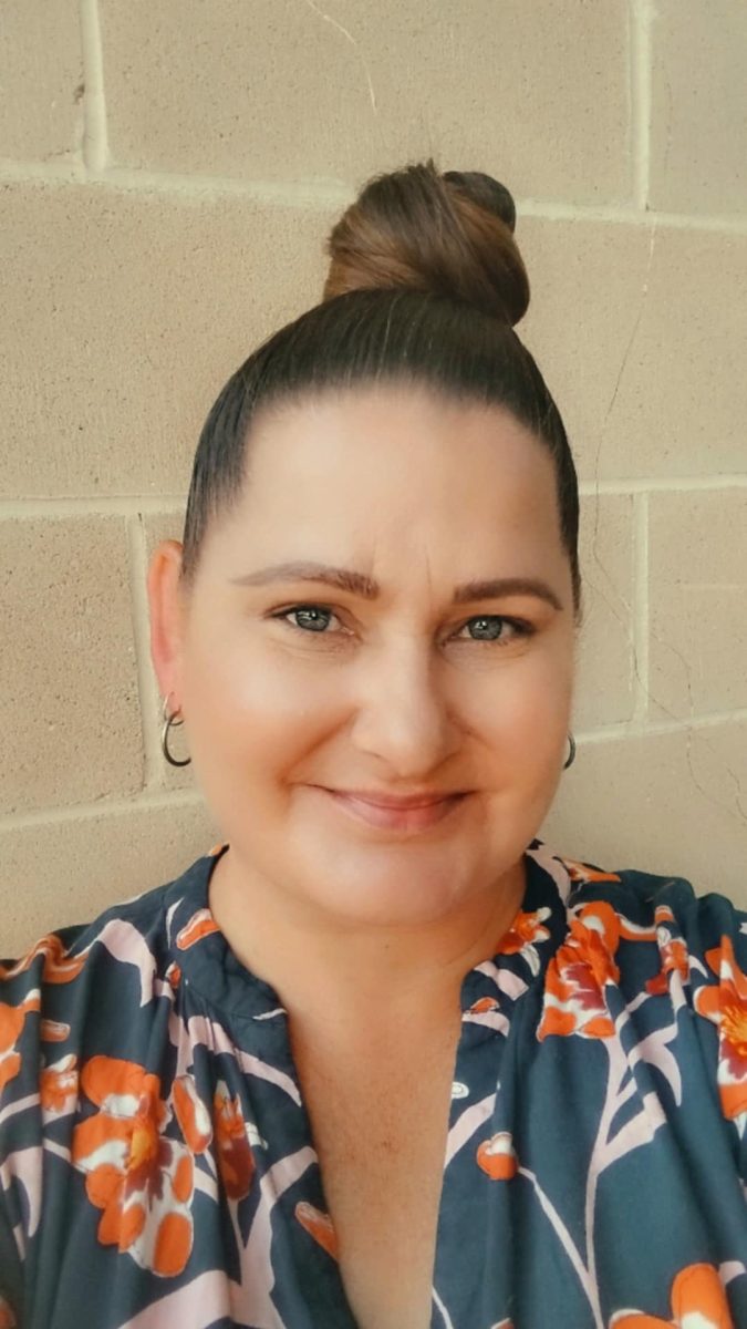 A smiling woman with her hair in a high bun