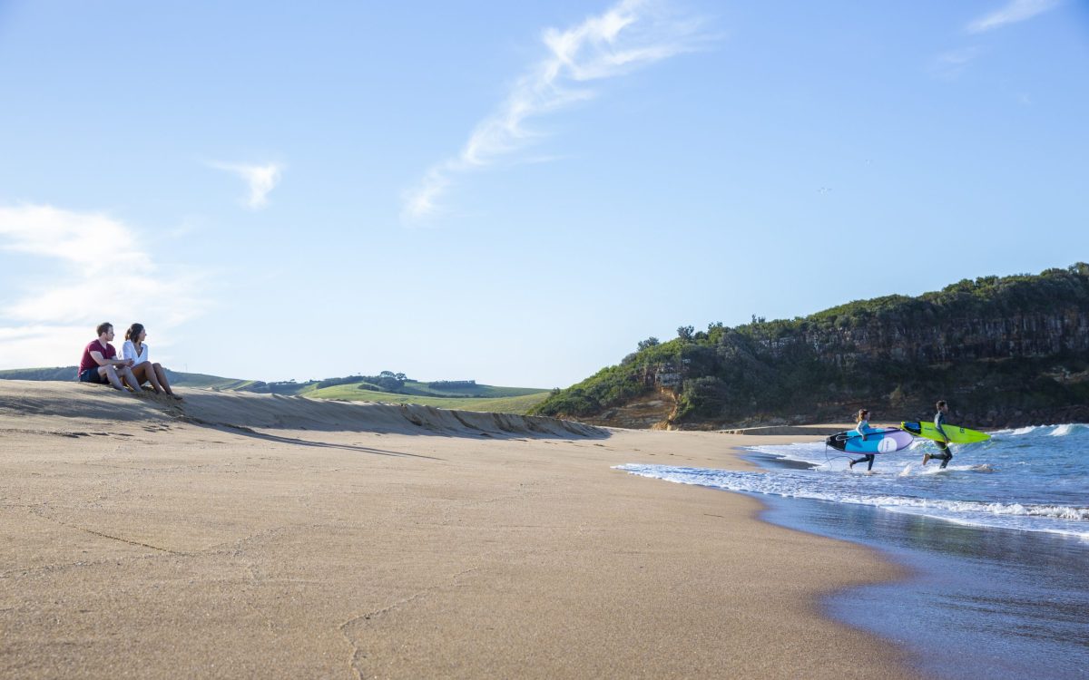 Couple heading into the surf at Werri Beach.