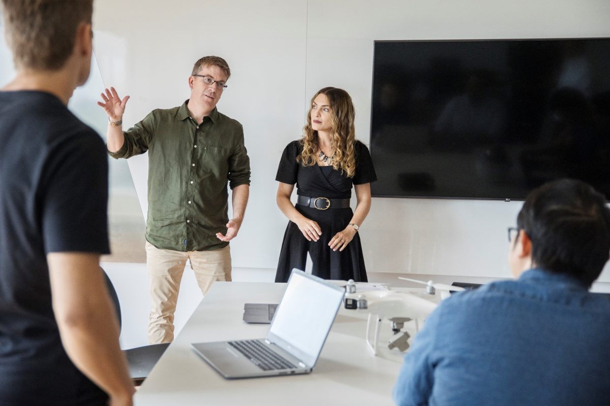 Two people presenting to team in a boardroom.