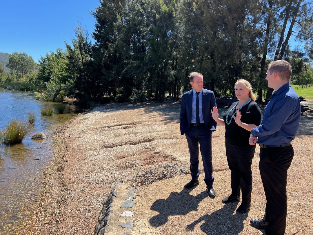 Three people standing at a riverbank