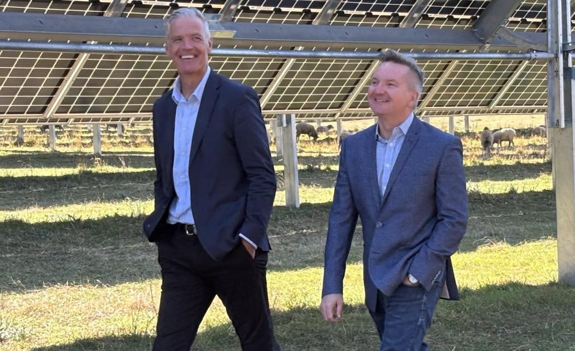 Tony Mahar and Chris Bowen walking alongside some solar panels.